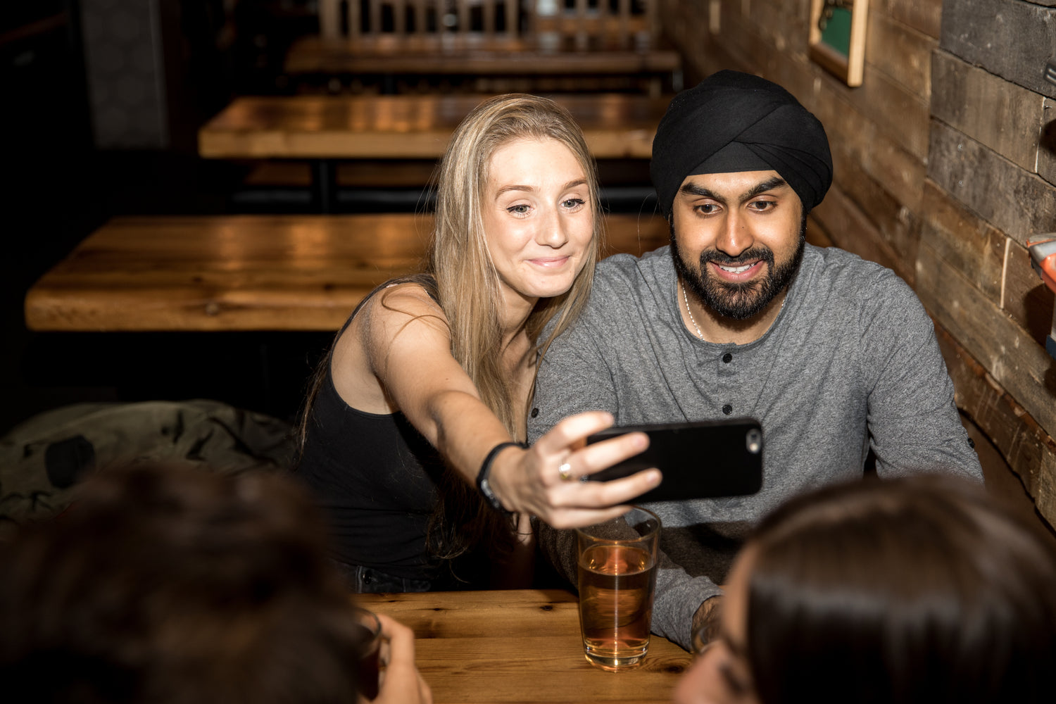 Man and woman taking a selfie at the bar while playing Connectin' Card Game.